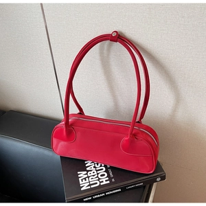 Close-up of vibrant red leather shoulder bag featuring silver zipper and glossy finish