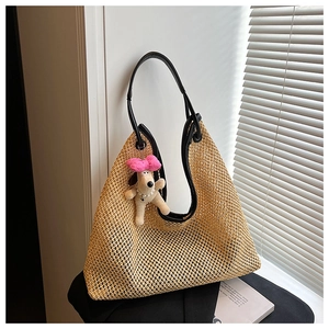 Detail of woven straw tote bag with black leather handles and cute plush dog pendant