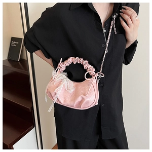 Sac croissant rose avec nœud en dentelle et perle porté par un mannequin