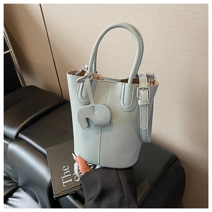 Detail of light blue bucket bag in litchi leather with adjustable strap and elephant charm