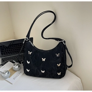 Detail of black pleated shoulder bag with silver butterfly charms and urban accessories