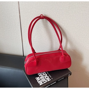 Macro detail of red leather handbag with silver zipper and long dual straps on a book