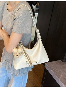 Sac à main beige en cuir grainé avec un petit pendentif ours en peluche sur l'anse