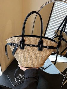 Woven straw tote bag with black leather handles and metal buckles on a mirror background
