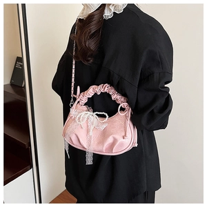 Détail du sac croissant rose avec nœuds en dentelle, perles et poignée froncée