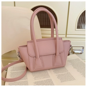 Detail of pink lychee grain faux leather handbag on a book with soft lighting