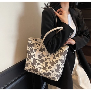 Detail view of large cow print canvas tote bag carried on shoulder for daily commute