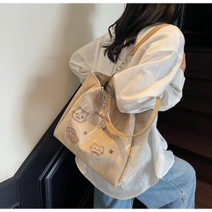 Détail du cabas beige avec broderie de chat, bandoulière en chaîne et texture froissée