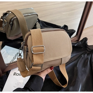 Detailweergave van de kaki canvas crossbodytas met ritssluitingen en een spiegelreflectie