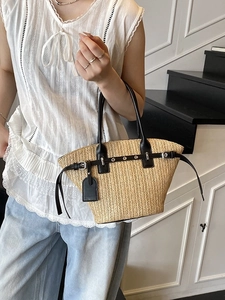 Woven straw tote bag with black leather straps and silver eyelets for beach vacations