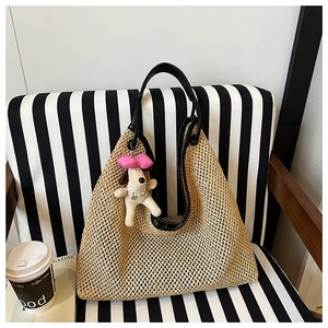 Detail of straw woven tote with black leather handles and cute plush dog charm