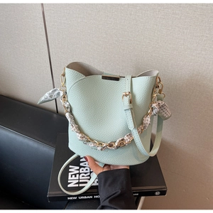 Macro detail of mint green litchi leather bucket bag with gold chain and silk scarf wrap