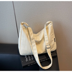 Detail of creamy yellow nylon crescent bag featuring adjustable strap and silver hardware