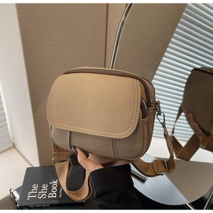 Detail van canvas crossbodytas met brede stoffen riem en zilveren metalen verstelgesp