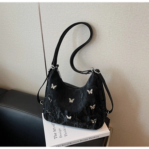 Detail of black pleated shoulder bag featuring metallic silver butterfly embellishments