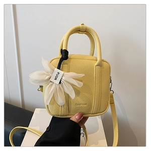 Detail of yellow boston bag featuring litchi texture leather and flower charm