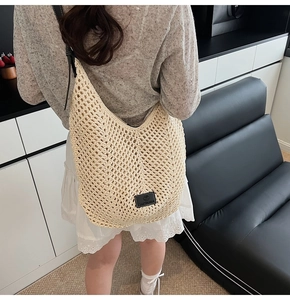 Close-up of beige crochet hobo bag with hollow knit texture and leather logo detail