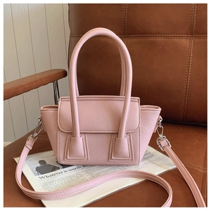 Detailed view of pink lychee leather bucket bag with top handle on a brown leather chair