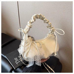 Détail du sac croissant blanc cassé avec nœud en dentelle et ornements de perles