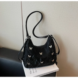 Detail of black pleated hobo bag featuring six silver butterfly ornaments and straps