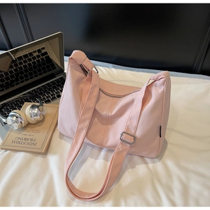Pink canvas hobo bag styled with a laptop and headphones in a minimalist urban setting