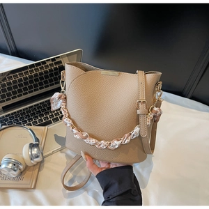 Détail du sac seau beige en cuir avec chaîne en foulard et accessoires de bureau