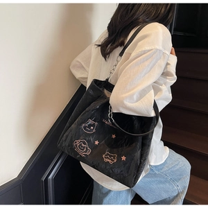 Détail du sac cabas noir avec motifs de chat roses et sangle en cuir et métal