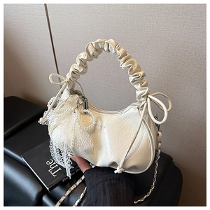 Détail du sac croissant crème en cuir plissé avec chaîne perles et nœud en dentelle