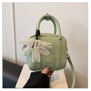 Close-up of mint green boston bag with litchi texture and mesh flower charm