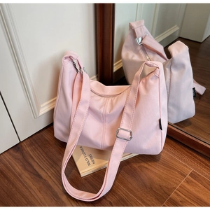 Close-up of light pink canvas dumpling bag with adjustable strap and metallic buckle