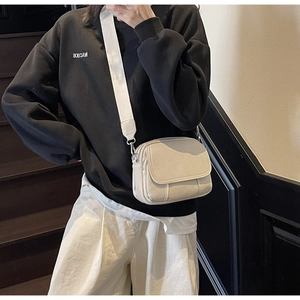 Detail van de roomwitte PU crossbody tas met brede riem gedragen door een model
