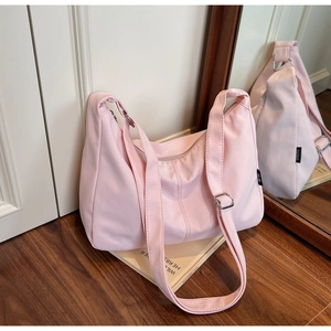 Close-up of pink canvas dumpling bag with adjustable shoulder strap and silver metal buckle
