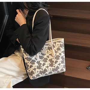 Detail shot of a large tote bag with cow print pattern on a vintage wooden staircase