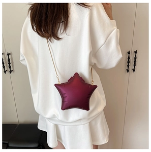 Detail of burgundy star-shaped crossbody bag with quilted stitching and gold chain strap