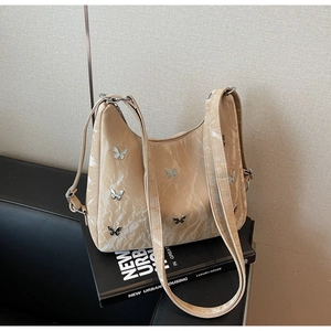 Detail of ruched apricot hobo bag featuring decorative silver metallic butterflies