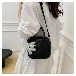 Detail of black pebbled leather Boston bag with a daisy charm and adjustable shoulder strap