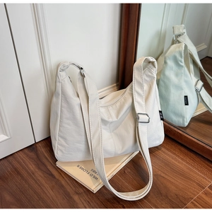 Detail of white crescent canvas bag with adjustable silver buckle and black side brand tag