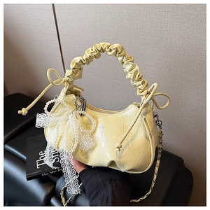 Détail du sac à main en cuir froncé jaune clair avec breloque en dentelle et perles