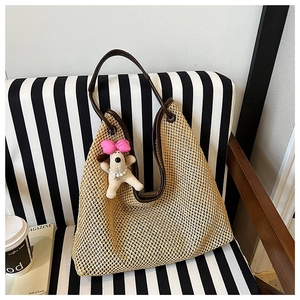 Detail view of woven straw tote bag with brown leather trim and a cute puppy plush charm