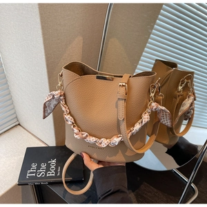 Détail d'un sac seau en cuir grainé beige avec poignée foulard et boucle dorée
