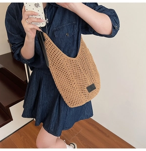 Detailed texture of khaki woven hobo bag with black leather strap on a model