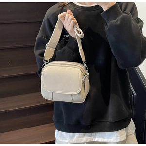 Detail van beige crossbodytas met brede riem gedragen bij een casual modieuze outfit
