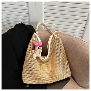 Detail of woven straw bag with cream leather handle and cute puppy plush pendant charm