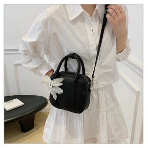 Detail of black pebbled leather Boston bag with 3D white flower decor and logo