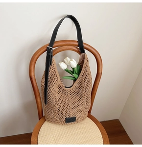 Detail of hollow woven brown hobo bag featuring black leather strap and metal buckle