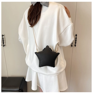 Rear view of model wearing a black star-shaped quilted crossbody bag with gold chain