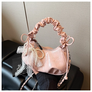 Détail du sac croissant en cuir verni plissé rose avec nœud en dentelle et perles