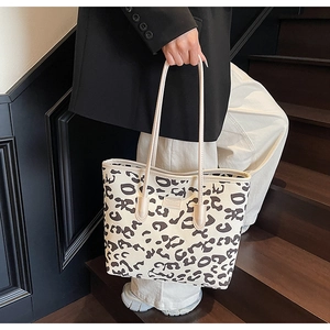 Detail of large leopard print tote bag with double shoulder straps on urban stairs