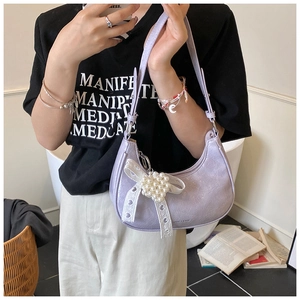 Detail view of light purple hobo bag with pearl heart and lace bow on a model