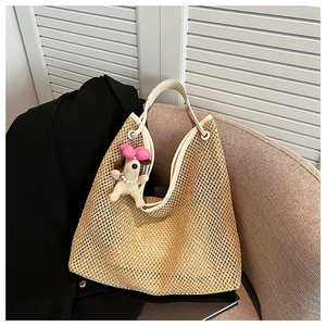 Detailed view of straw tote bag featuring white leather trim and pink bow puppy charm
